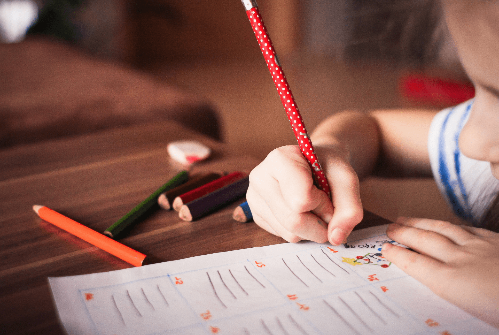 young child writing with a red pencil back to the routine