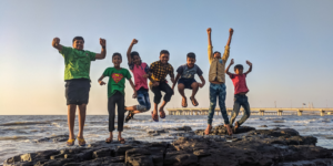 kids jumping together on a rock near the ocean celebrating Earth Day