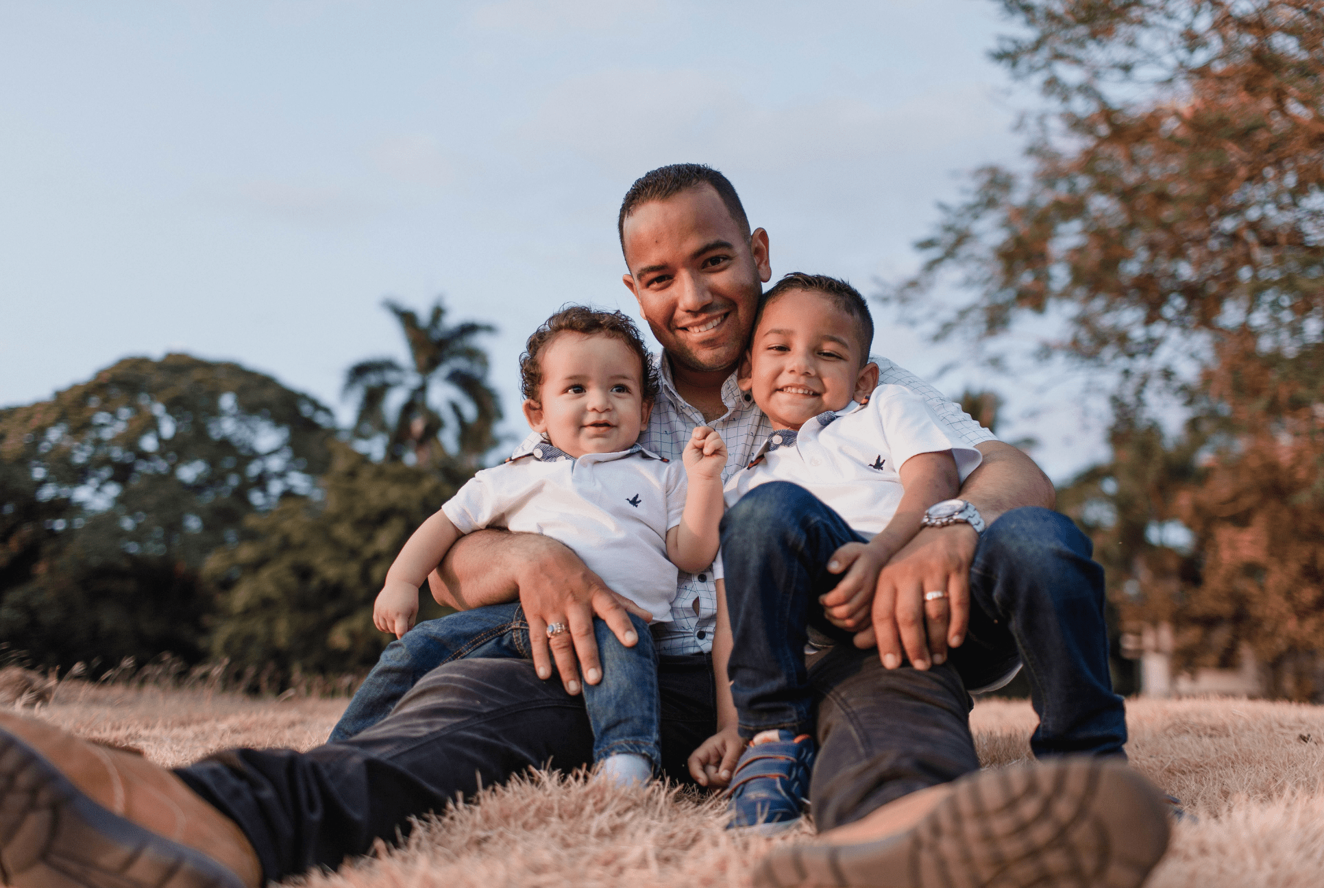 two young boys sit on their father's lap