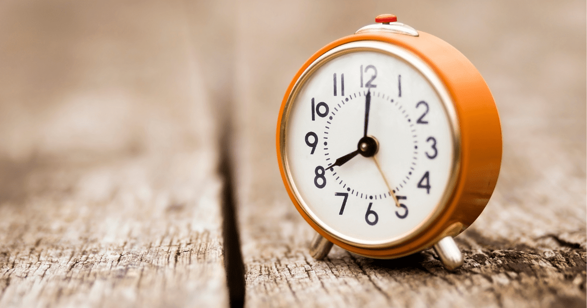 orange clock on a wood table end of daylight savings survival guide