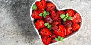 white heart shaped bowl full of heart shaped strawberries