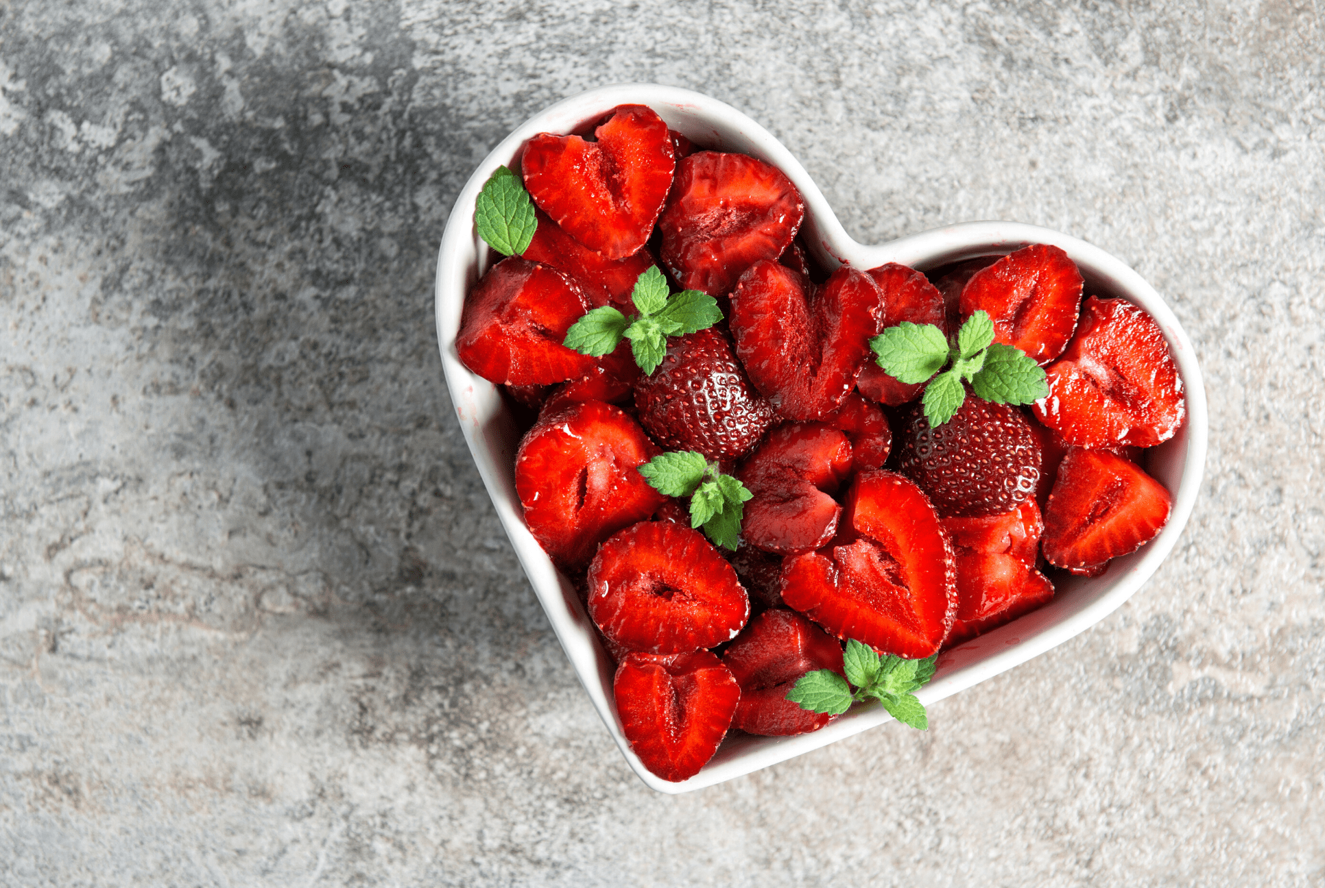 white heart shaped bowl full of heart shaped strawberries