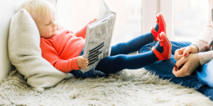 young boy reading a book in bed