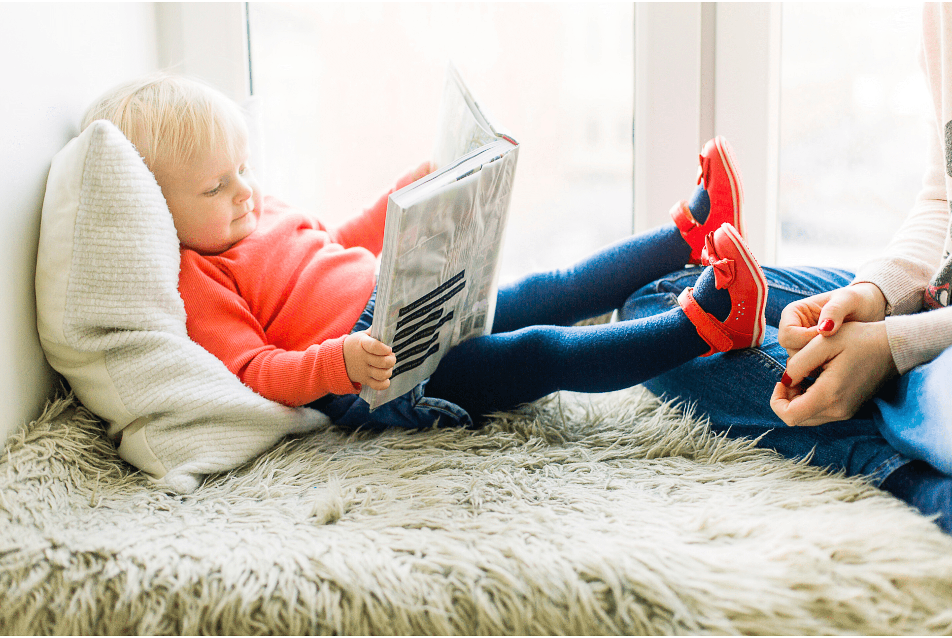 young boy reading a book in bed