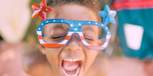 black boy with patriotic and fun sunglasses smiles