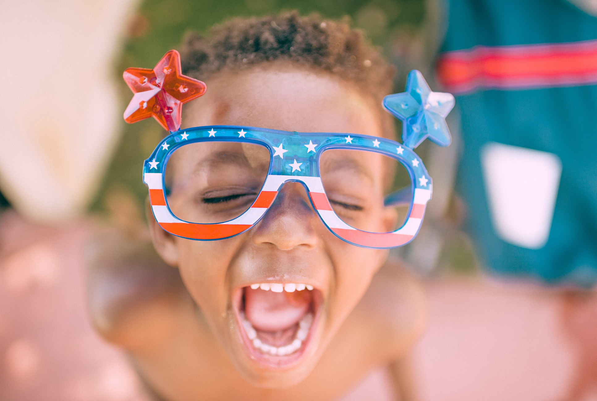 black boy with patriotic and fun sunglasses smiles