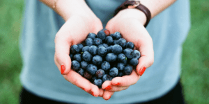 woman holds handful of blueberries