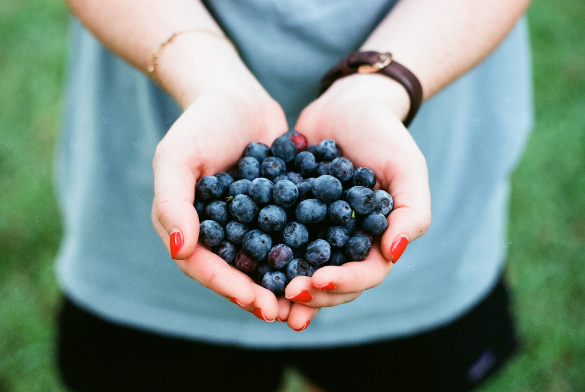 woman holds handful of blueberries
