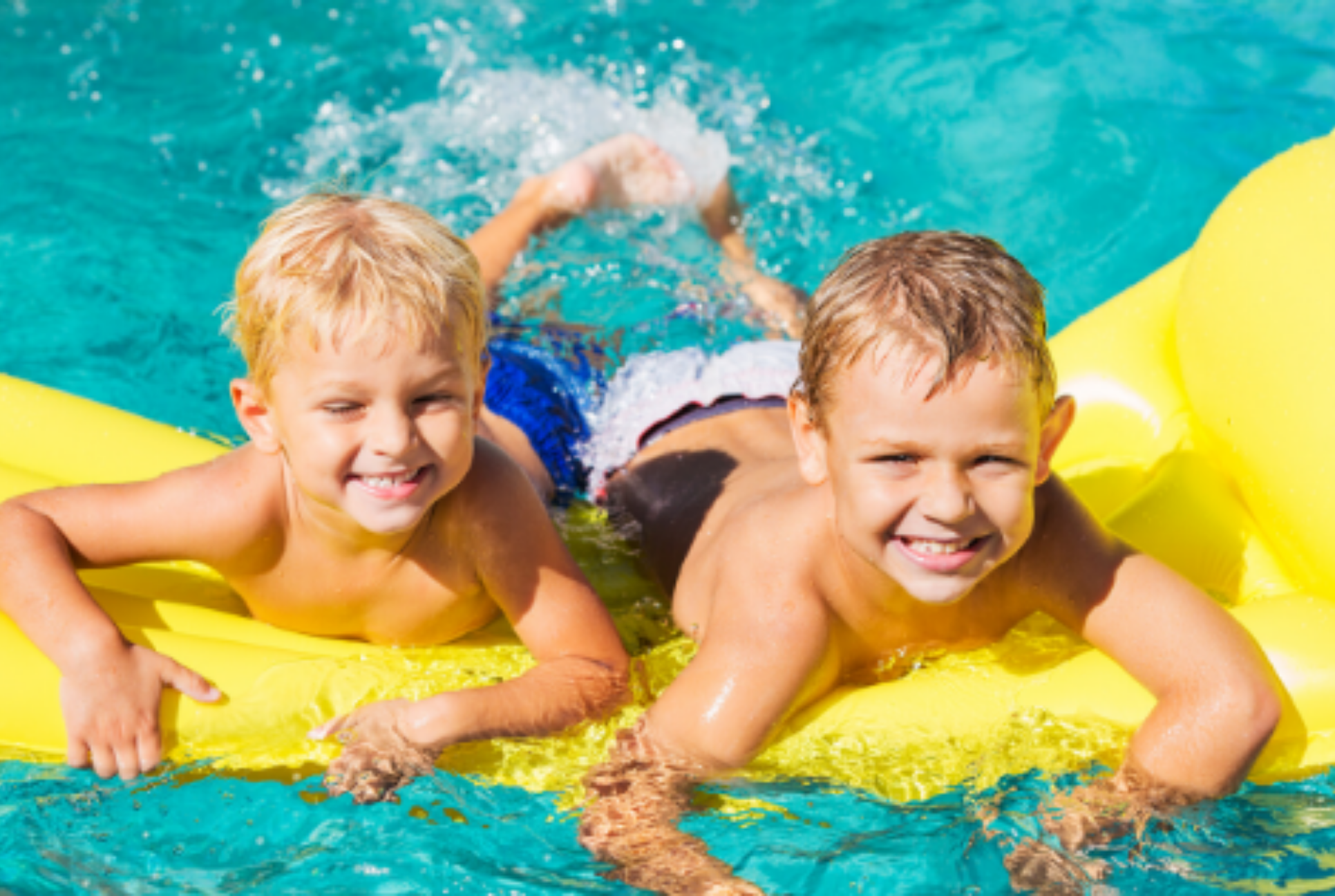 Two boys smile on a yellow pool float